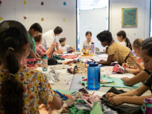 A group of children engaged in crafting activities around a table, showcasing creativity and collaboration.
